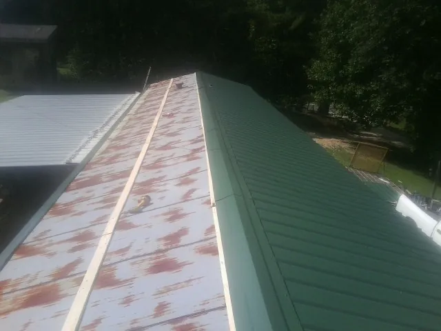 Old rusted panels beside newly installed green metal roofing — Wind Damage Roof Repair by Roofing Brothers in Rumson
