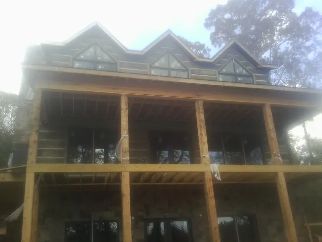 Dormers and porch framing on a large log home under construction — Roof Coating work by our crew in Rumson
