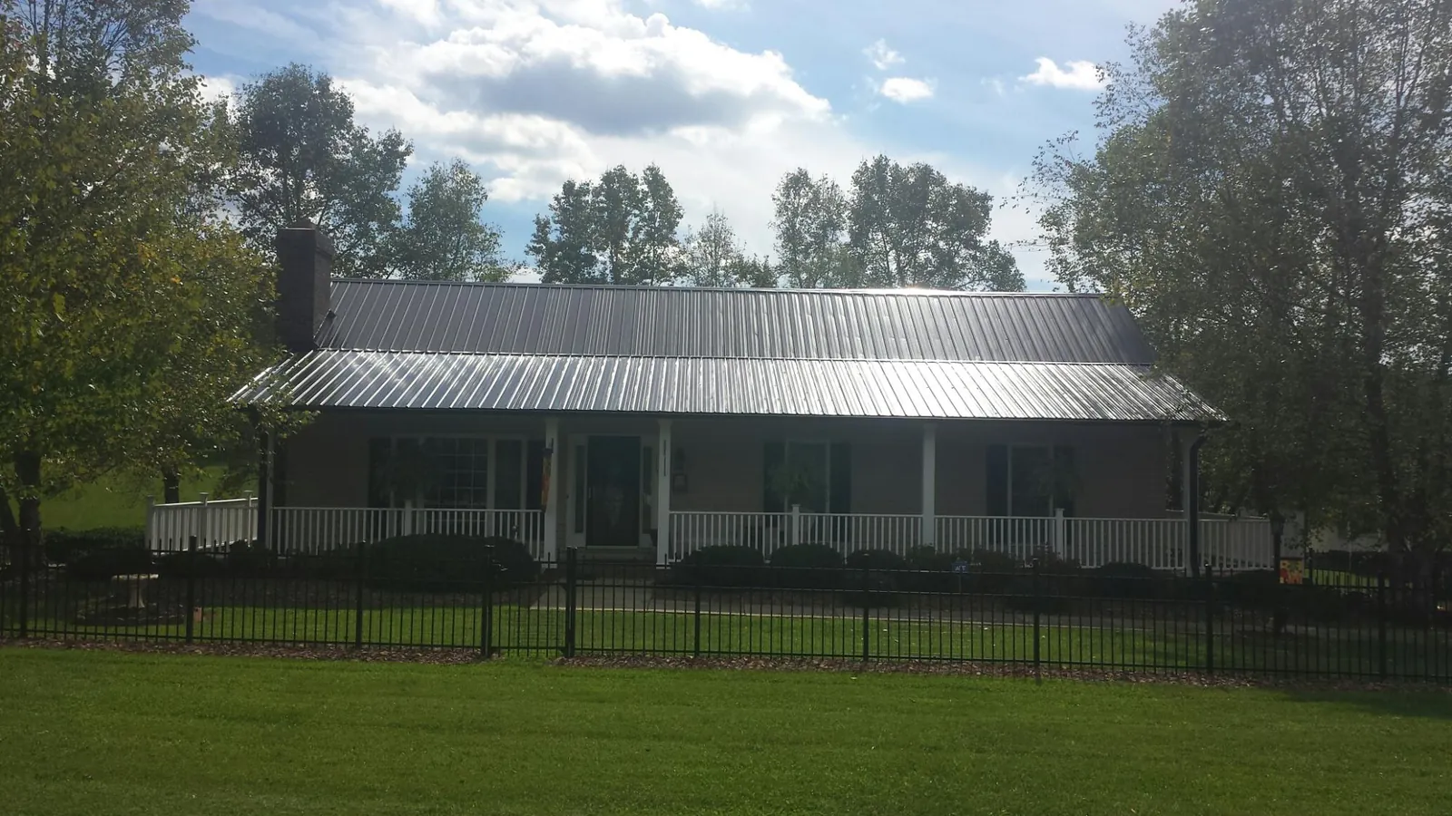 Gray metal roof on a brick ranch with a full width front porch — Gutter Guard Installation work by our crew in Rumson