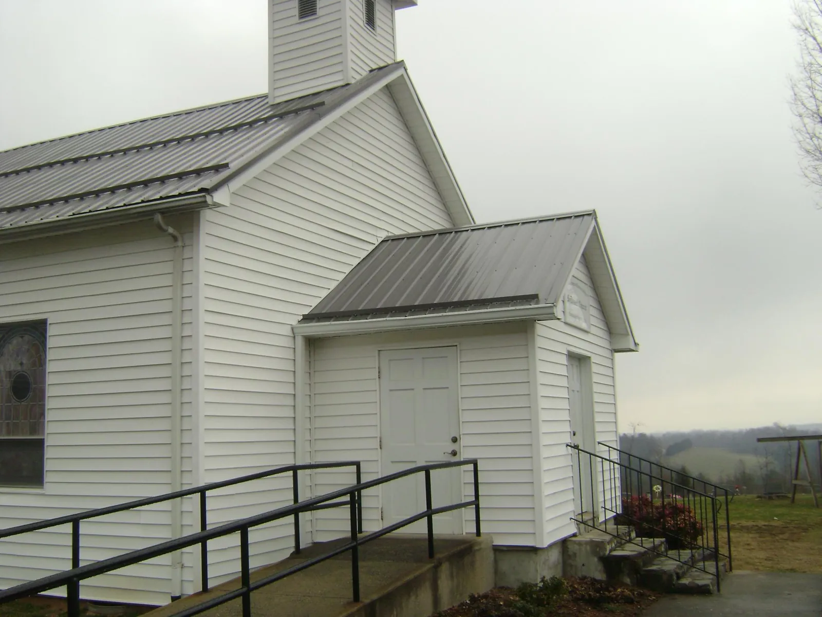 Gray metal roof on a white clapboard church with a steeple in Rumson