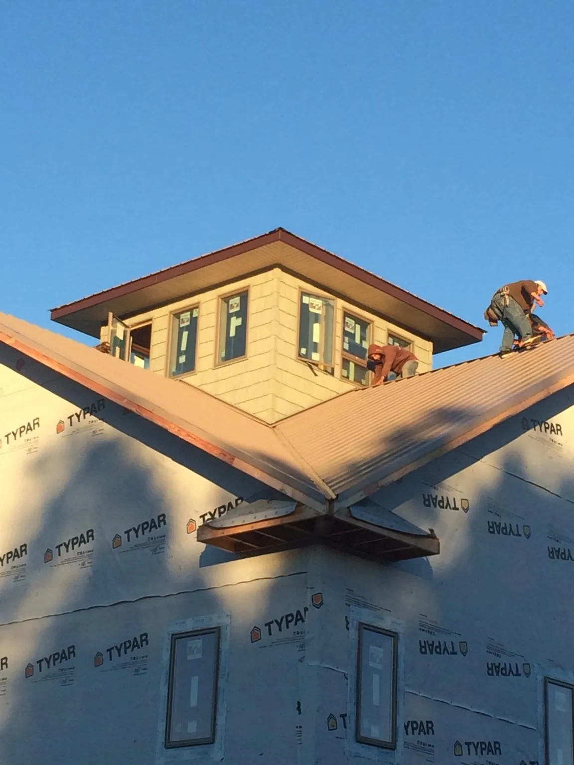 Roofers working around a rooftop cupola on a new metal roof at sunset — Roof Waterproofing in Rumson by Roofing Brothers